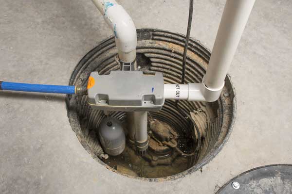 A sump pump system installed in a basement floor with connected pipes.