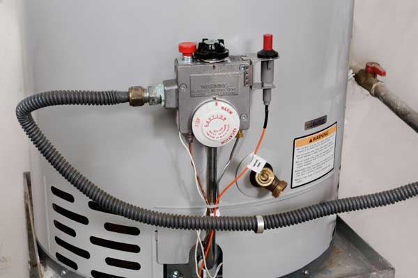 Close-up of a water heater's pressure relief valve and attached components.