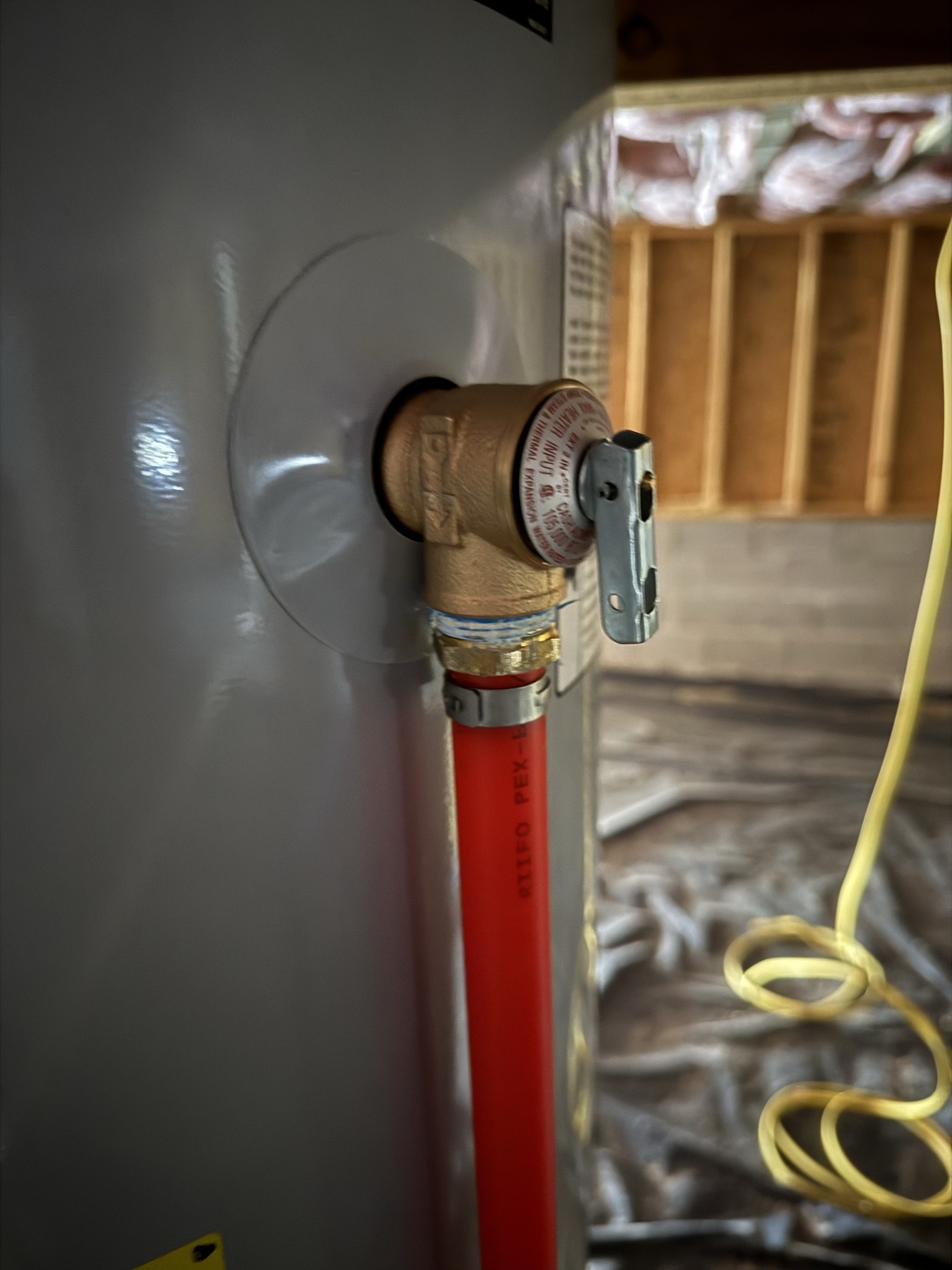 Close-up of a water heater valve connected to a red pipe.