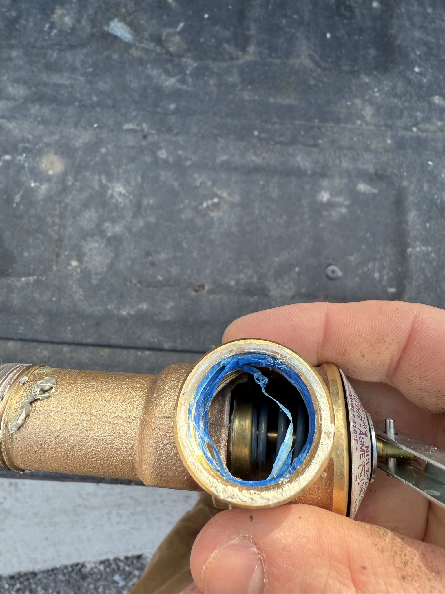 Close-up of a hand holding a brass valve with internal components visible.